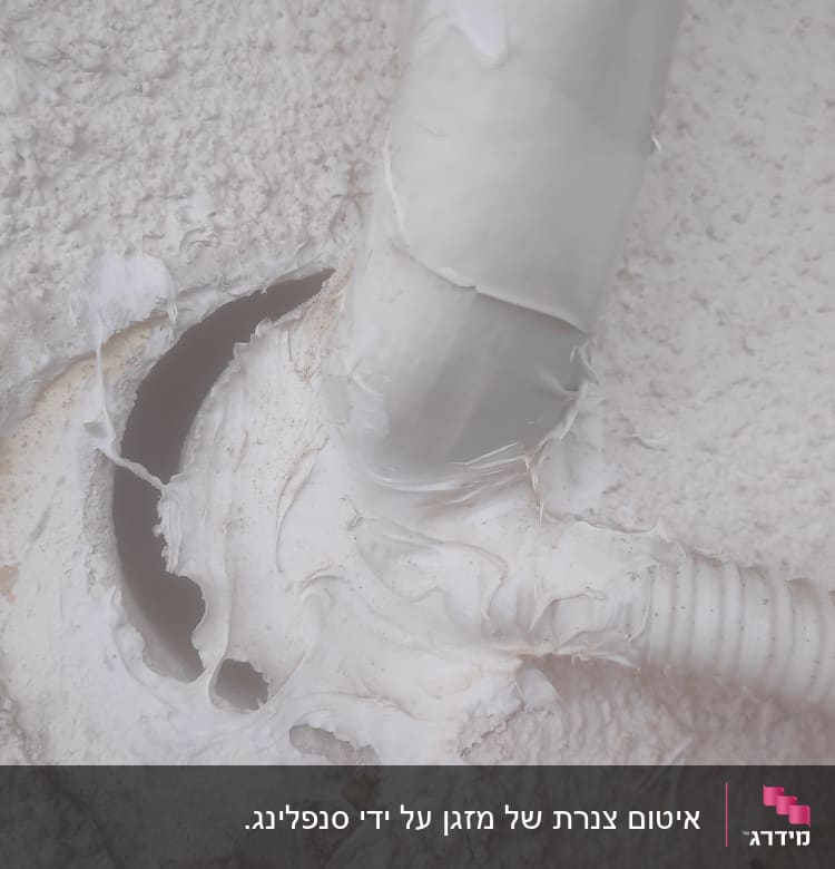 צינור לבן מחובר לקיר עם חומר איטום